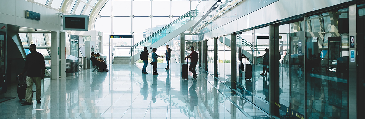 The inside of a modern airport with some people in waiting around an airport train platform