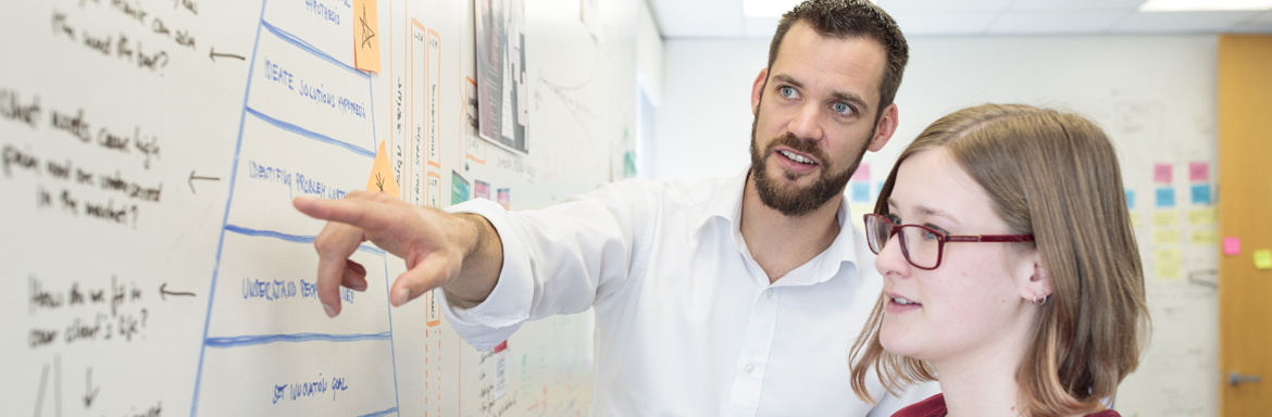 Two Jade employees at a whiteboard discussing the details on the board